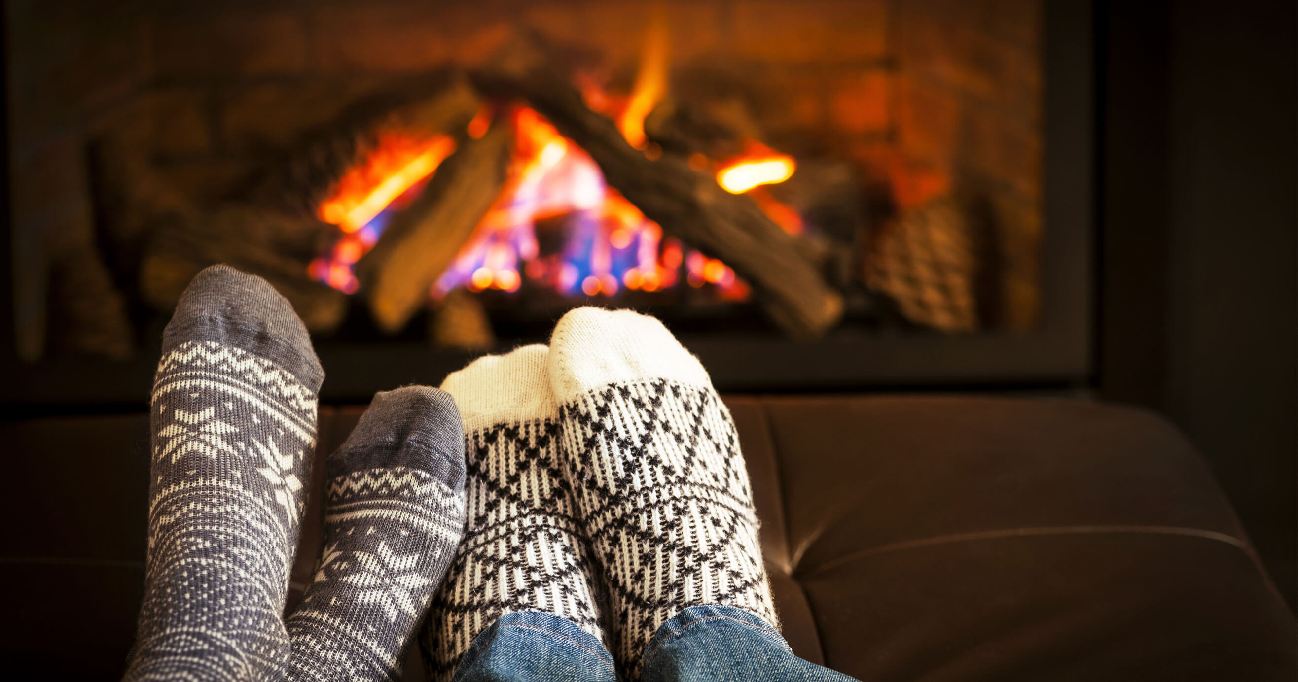 A couple putting their feet up by the warm fire.